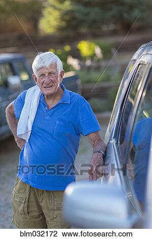 Stock Image - Senior Caucasian man leaning against car. Fotosearch