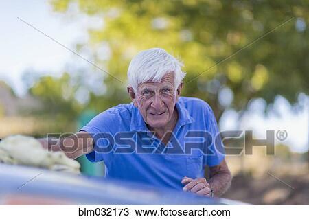 Stock Image - Senior Caucasian man washing car outdoors. Fotosearch