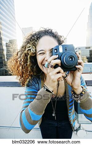 Stock Photograph - Woman photographing on urban rooftop. Fotosearch