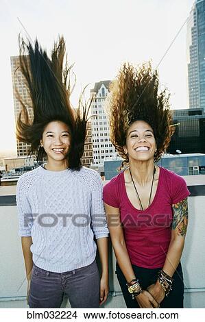 Picture - Women tossing their hair on urban rooftop. Fotosearch
