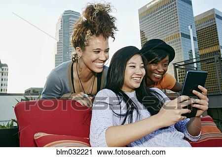 Stock Image - Women using digital tablet on urban rooftop. Fotosearch