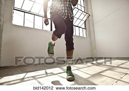 Stock Image - African American man dancing in loft. Fotosearch