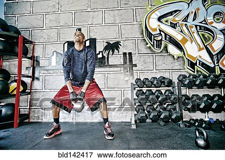 Stock Photo - African American man lifting weights in gym. Fotosearch