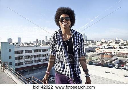 Stock Image - African American man standing on urban rooftop. Fotosearch
