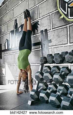 Stock Photo - African American woman doing handstand in gym. Fotosearch