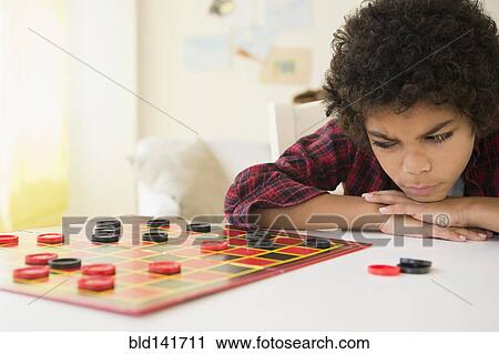Stock Image - Angry mixed race boy losing game of checkers. Fotosearch