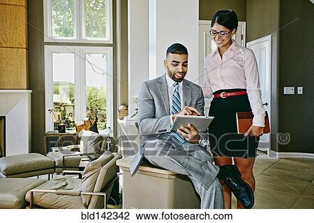Stock Image - Business people using digital tablet together at home. Fotosearch