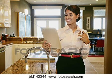 Picture - Businesswoman using digital tablet in kitchen. Fotosearch