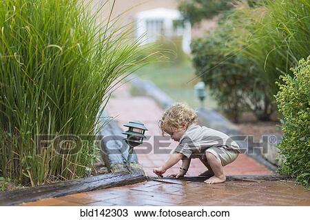 Stock Image - Caucasian baby boy playing on brick walkway. Fotosearch