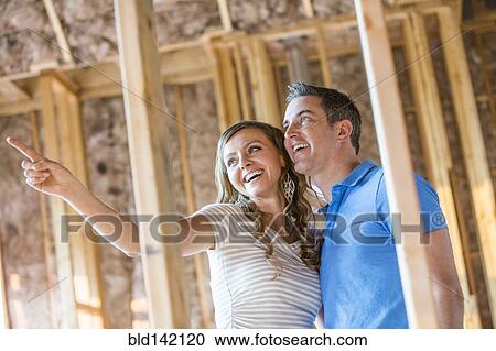 Stock Image - Caucasian couple admiring house under construction. Fotosearch