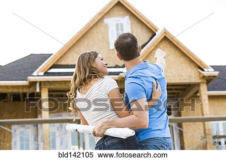 Stock Photography - Caucasian couple admiring house under construction. Fotosearch