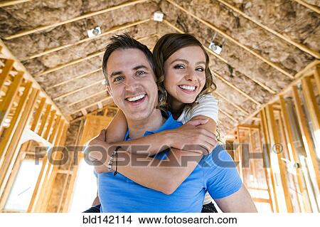 Picture - Caucasian couple hugging in house under construction. Fotosearch