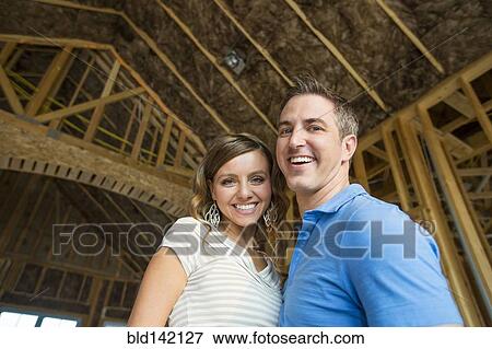 Stock Photo - Caucasian couple hugging in house under construction. Fotosearch