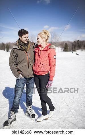 Stock Photo - Caucasian couple ice skating on frozen lake. Fotosearch