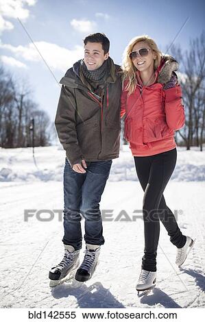 Stock Photography - Caucasian couple ice skating on frozen lake. Fotosearch