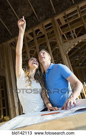 Caucasian couple pointing at ceiling under construction View Large Photo Image Stock Image - Caucasian couple pointing at ceiling under construction. Fotosearch