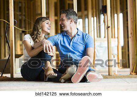 Stock Photography - Caucasian couple sitting on floor in house under construction. Fotosearch