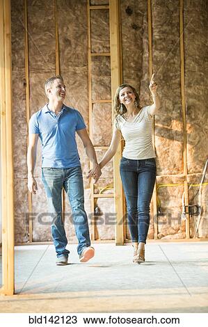 Caucasian couple walking in house under construction View Large Photo Image Stock Image - Caucasian couple walking in house under construction. Fotosearch