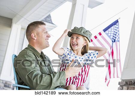 Stock Photo - Caucasian daughter wearing hat of soldier father. Fotosearch