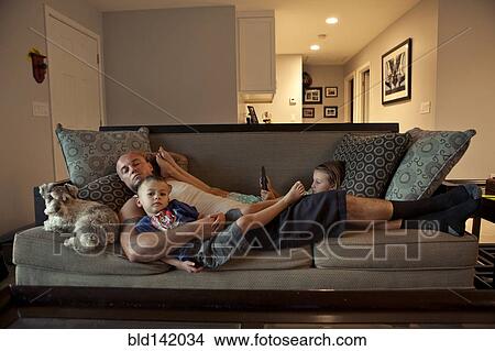 Picture - Caucasian father and children relaxing on sofa. Fotosearch
