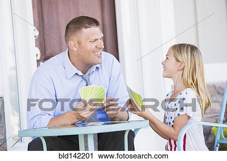 Stock Image - Caucasian father and daughter playing cards. Fotosearch