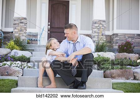 Stock Image - Caucasian father and daughter sitting on front stoop. Fotosearch