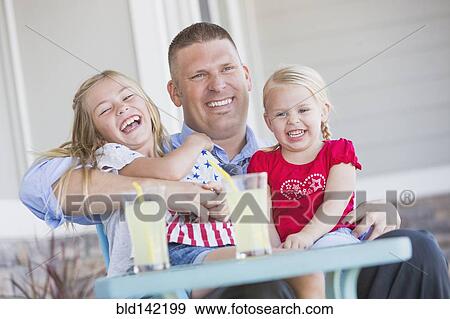 Stock Photo - Caucasian father and daughters laughing on porch. Fotosearch