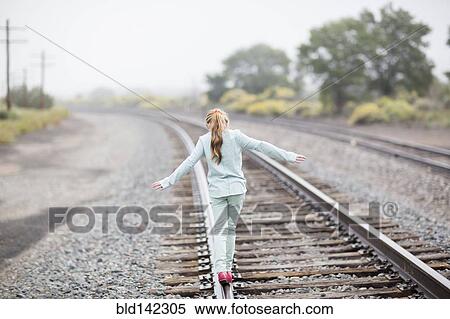 Caucasian girl balancing on train tracks View Large Photo Image Stock Photography - Caucasian girl balancing on train tracks. Fotosearch