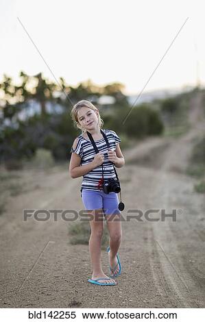 Caucasian girl carrying camera on rural dirt road View Large Photo Image Stock Photography - Caucasian girl carrying camera on rural dirt road. Fotosearch
