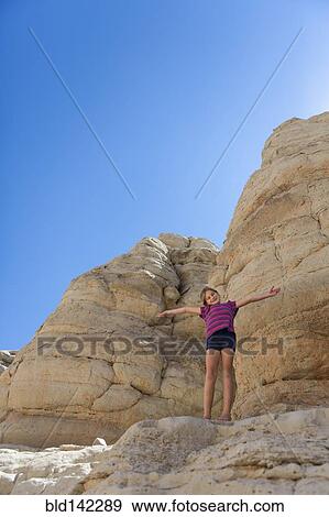 Stock Photo - Caucasian girl cheering on rock formations. Fotosearch