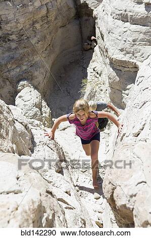 Stock Image - Caucasian girl climbing rock formations. Fotosearch