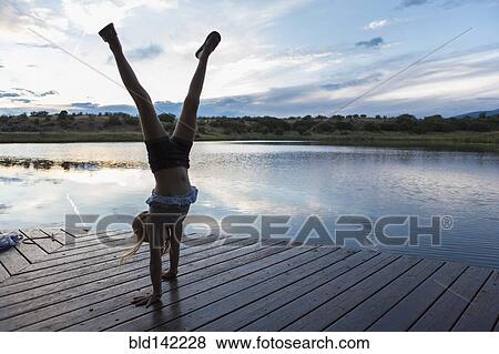 Caucasian girl doing handstand on wooden deck near lake View Large Photo Image Stock Photo - Caucasian girl doing handstand on wooden deck near lake. Fotosearch