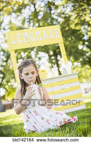 Picture - Caucasian girl drinking at lemonade stand. Fotosearch
