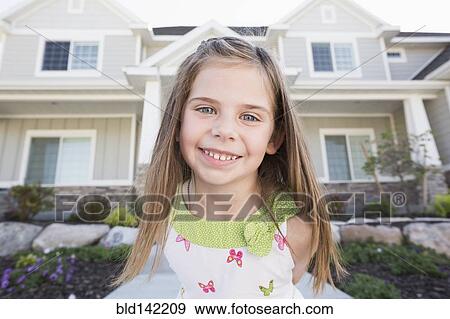 Stock Photo - Caucasian girl smiling outside house. Fotosearch