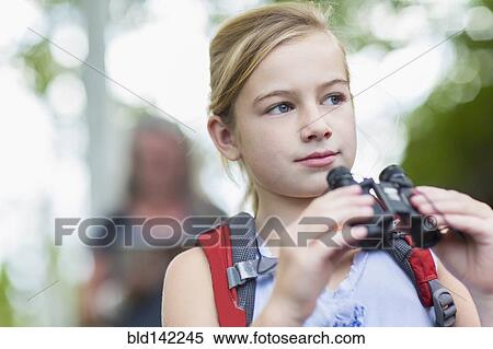 Stock Photography - Caucasian girl using binoculars in forest. Fotosearch