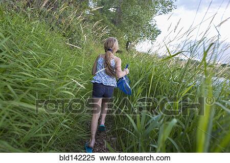 Stock Photography - Caucasian girl walking in tall grass. Fotosearch
