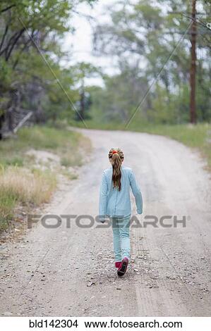 Picture - Caucasian girl walking on rural dirt road. Fotosearch