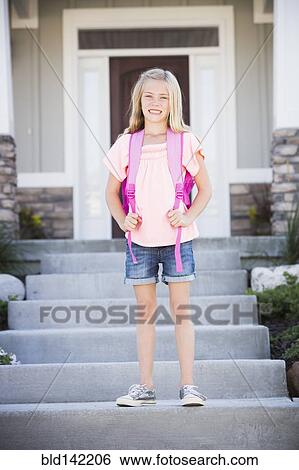 Stock Photograph - Caucasian girl with backpack smiling on front stoop. Fotosearch