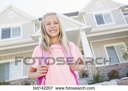 Stock Photo - Caucasian girl with backpack smiling near house. Fotosearch