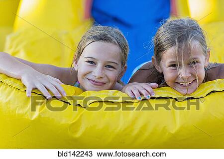 Stock Image - Caucasian girls playing together on inflatable castle. Fotosearch