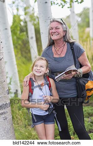Picture - Caucasian grandmother and granddaughter hiking in forest. Fotosearch
