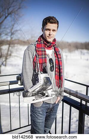 Stock Photo - Caucasian man carrying ice skates in winter. Fotosearch