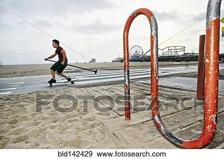 Caucasian man skateboarding with paddle pole at beach View Large Photo Image Stock Photo - Caucasian man skateboarding with paddle pole at beach. Fotosearch