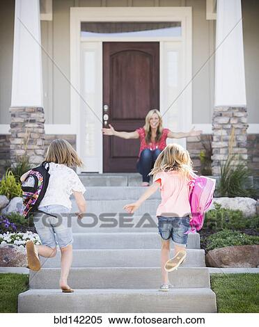 Stock Photography - Caucasian mother greeting daughters returning home from school. Fotosearch