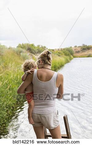 Stock Photograph - Caucasian mother holding baby son near lake. Fotosearch