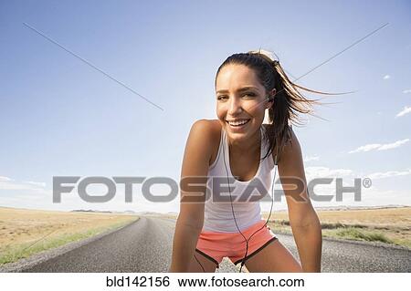 Stock Photograph - Caucasian runner resting on remoter road. Fotosearch