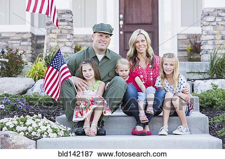 Stock Photo - Caucasian soldier and family smiling together on front stoop. Fotosearch