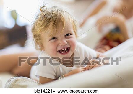 Picture - Caucasian toddler boy laughing on sofa. Fotosearch
