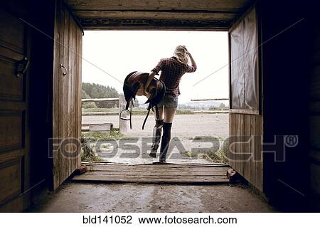Caucasian woman carrying horse saddle in barn doorway View Large Photo Image Stock Image - Caucasian woman carrying horse saddle in barn doorway. Fotosearch