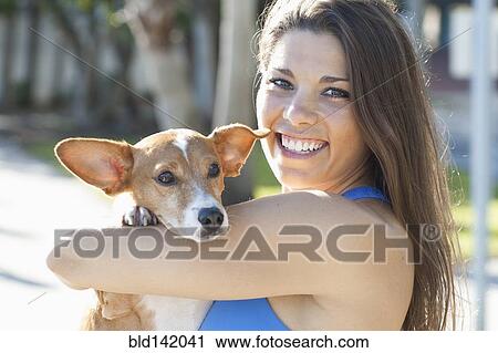 Stock Image - Caucasian woman holding pet dog outdoors. Fotosearch